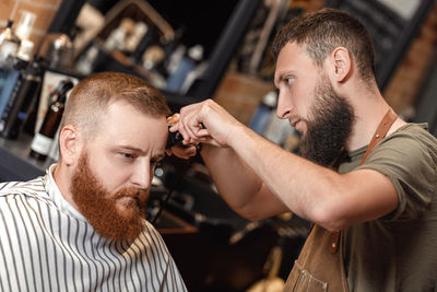 Barber trimming hair of customer