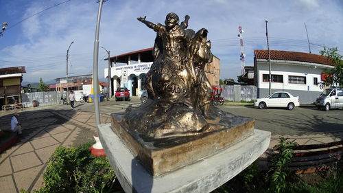 Statue in city against sky