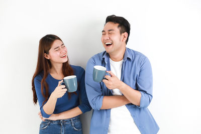 Happy young man using phone against white background