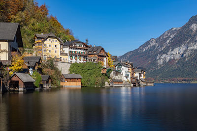 Houses by lake and buildings against sky