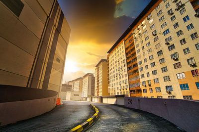 Empty road amidst buildings in city against sky