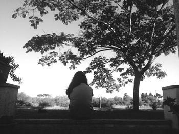 Rear view of woman sitting against clear sky