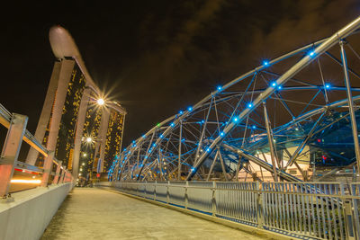 Modern bridge leading towards marina bay sands in city at night