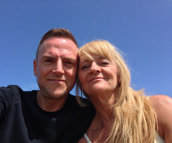 Portrait of mother and son against clear blue sky