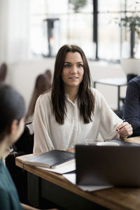 Smiling businesswoman with coworker at table during meeting