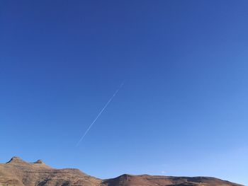 Low angle view of vapor trail against clear blue sky