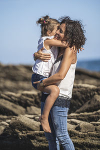 Mother and daughter on beach against sky