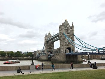 View of suspension bridge over river against cloudy sky