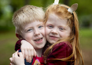 Portrait of happy siblings embracing at park