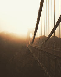 View of suspension bridge against sky during sunrise