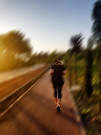 Rear view of woman running on road against sky