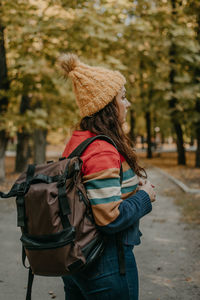 Rear view of woman wearing hat standing against trees during winter