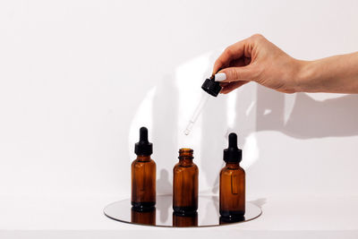 Close-up of hand holding bottle against white background