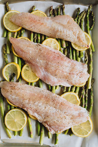 Raw pacific rockfish on a bed of asparagus and lemon wheels, sheet pan dinner