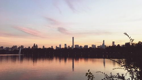 Scenic view of river by cityscape against sky during sunset