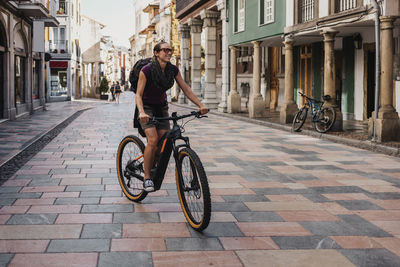 Man riding bicycle on street amidst buildings