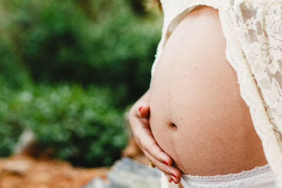 Midsection of pregnant woman standing outdoors