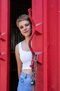 Portrait of woman standing against red door