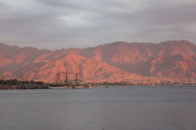 Scenic view of sea and rocky mountains against sky