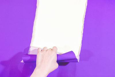 Low section of woman holding paper against pink background