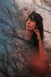 Double exposure of thoughtful woman and bare trees