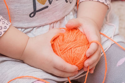 A small child is holding a ball of thread in his hands. the yarn is in the girl's palms