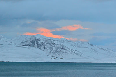 Scenic view of sea and snowcapped mountains against sky during winter