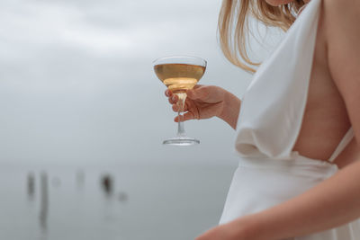 Midsection of woman holding wineglass