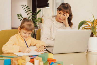 Working mom works from home office with kid. stressed woman using laptop.  woman freelancer