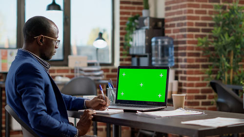 Rear view of man using laptop at office