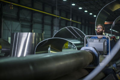 Worker operating machinery at control panel in steel factory