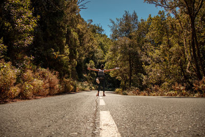 Rear view of person walking on road amidst trees