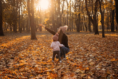 Happy family mom and baby girl playing outdoors in fall park. little girl and her mother 