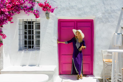 Woman standing against closed magenta door on sunny day