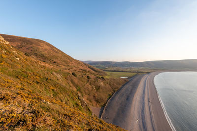 Scenic view of road leading towards mountains against clear blue sky