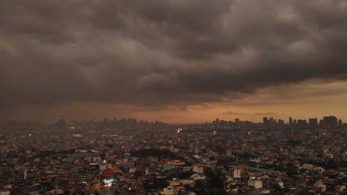 Aerial view of city against cloudy sky at dusk