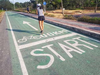 Rear view of woman standing on bicycle lane