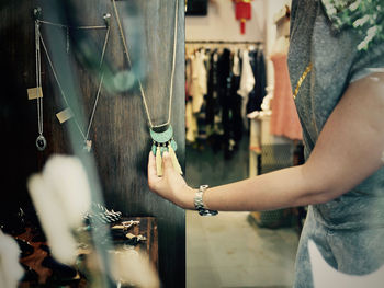 Midsection of woman buying necklace in store