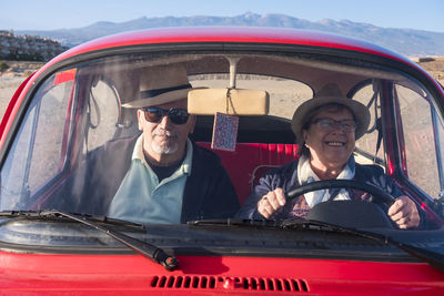 Senior couple sitting in car seen through windshield