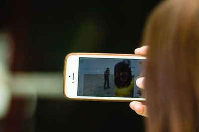 Close-up of woman photographing mobile phone