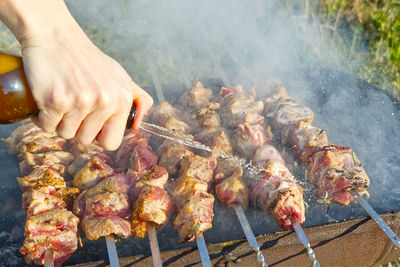 Midsection of person preparing food on barbecue grill