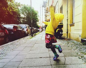 Full length of happy girl dancing on sidewalk