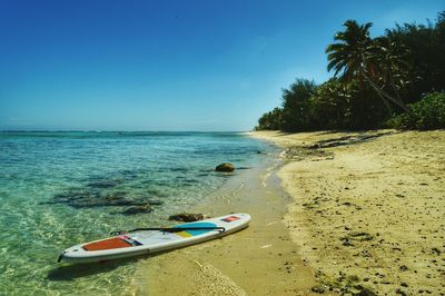 Paddleboard on beach against clear blue sky