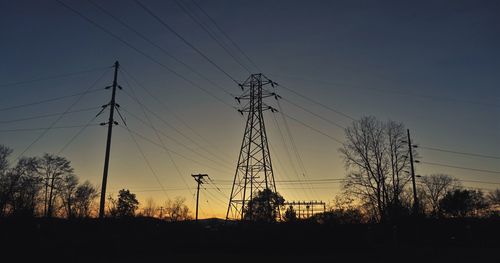 Low angle view of silhouette electricity pylon against sky during sunset