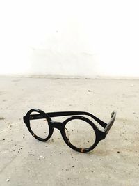 Close-up of eyeglasses on sand at beach against sky