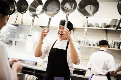 Male chef holding colanders while talking with colleague in commercial kitchen