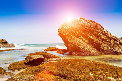 Scenic view of rocks on beach against sky