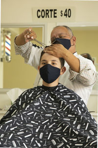 View of barber cutting hair of boy at barber shop