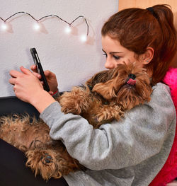 Woman with dog using mobile phone at home