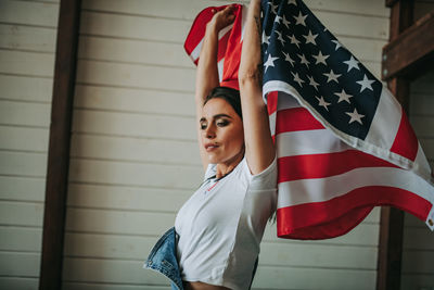 Woman with american flag against wall